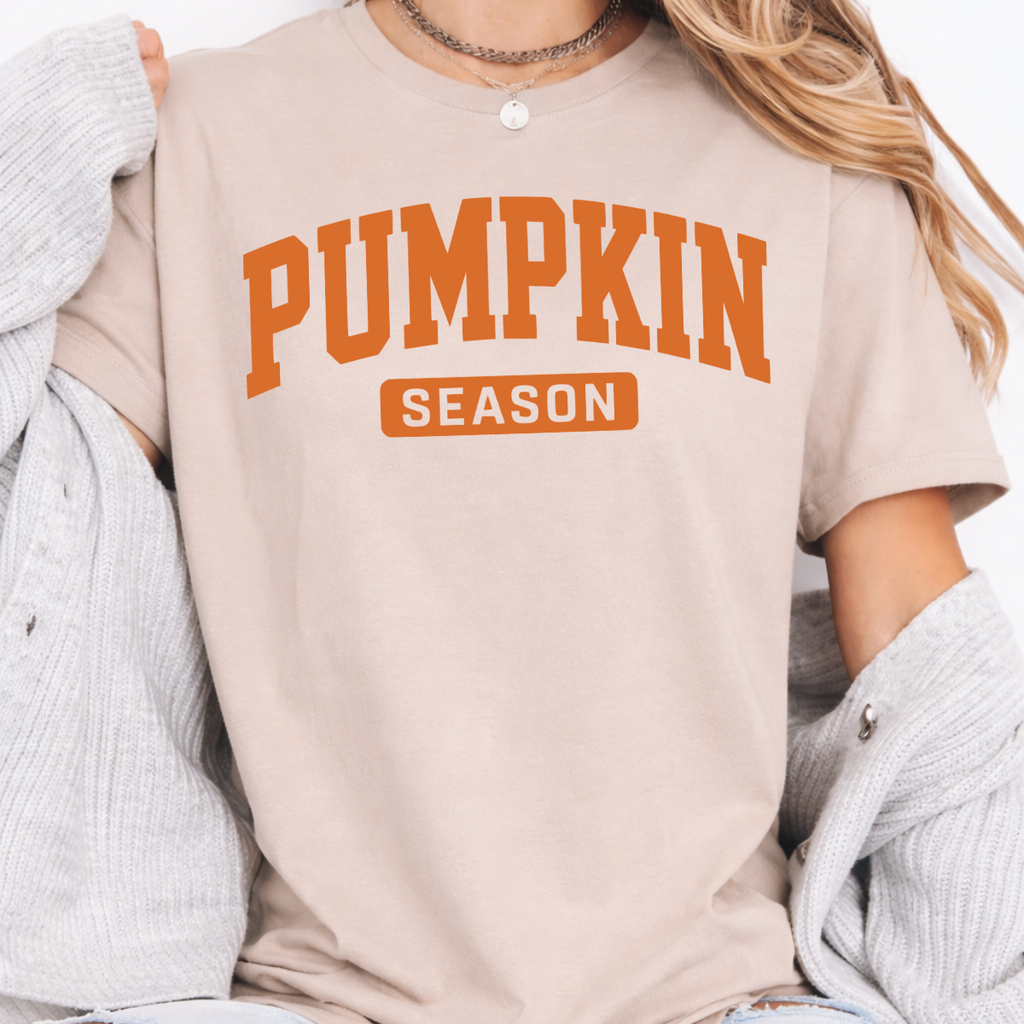 Woman wearing sand Pumpkin Season fall graphic tee with bold orange collegiate lettering.