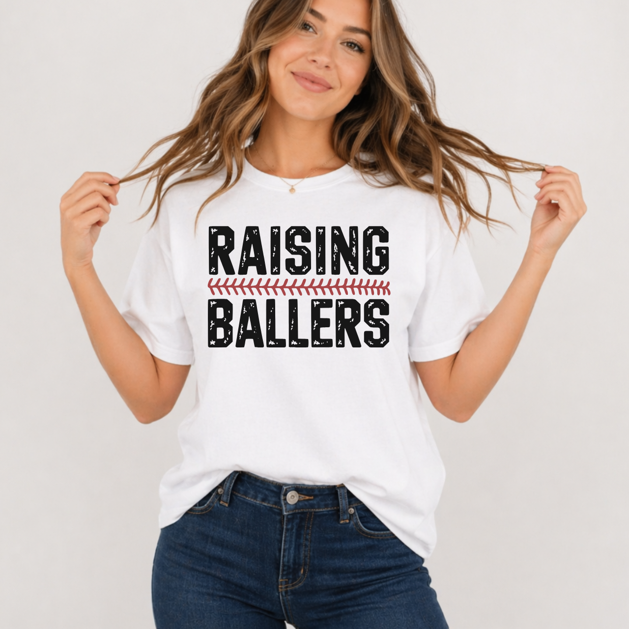 Woman wearing a white t-shirt with 'RAISING BALLERS' text on a plain background