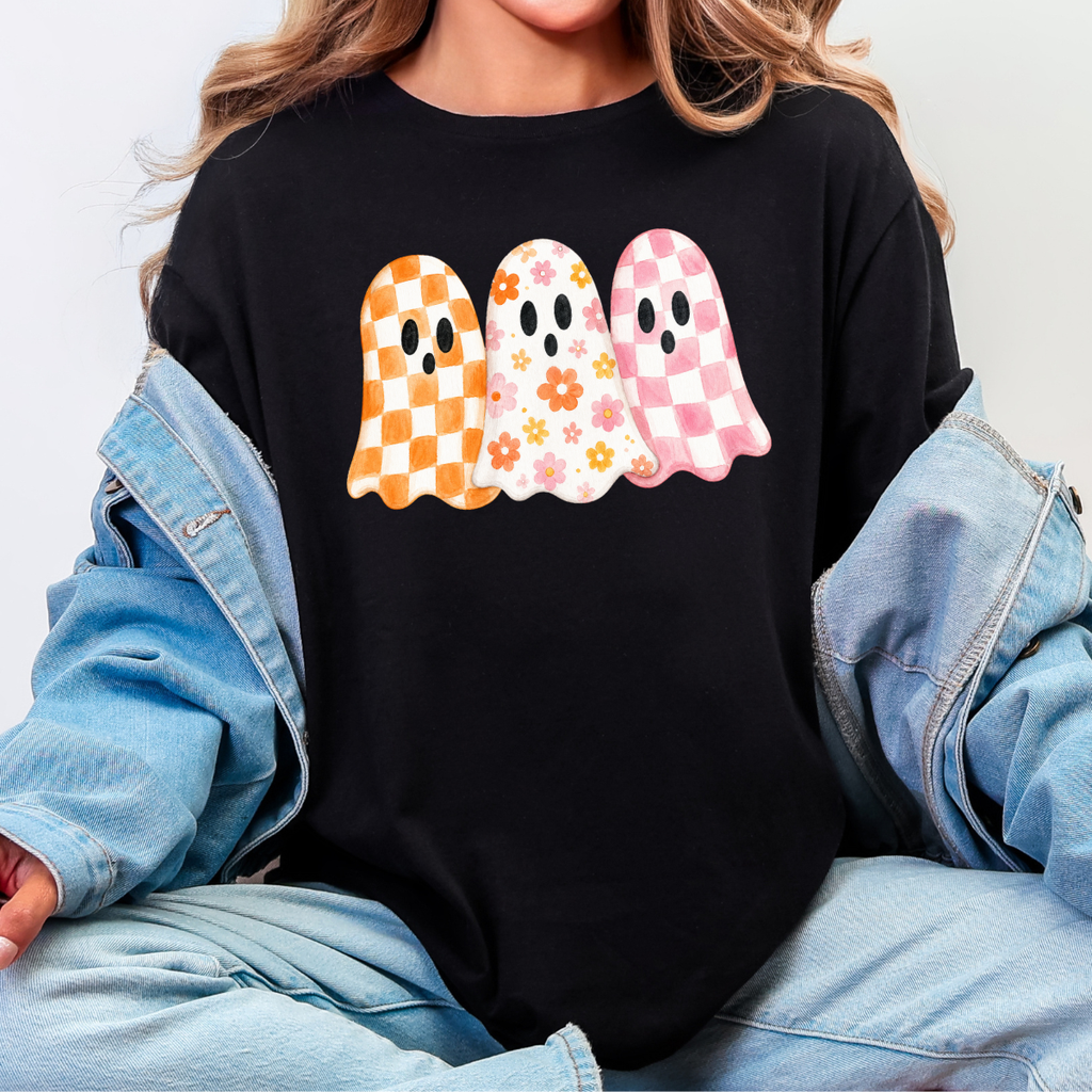 Woman wearing a black Halloween graphic tee with three orange, floral, and pink patterned ghosts.
