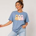 Woman wearing a stone blue Halloween graphic tee with three orange, floral, and pink patterned ghosts.