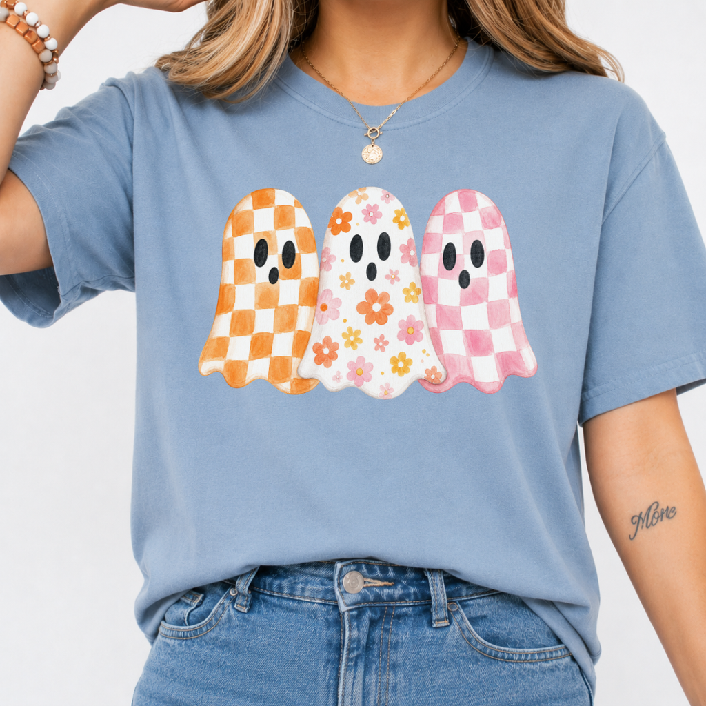 Woman wearing a stone blue Halloween graphic tee with three orange, floral, and pink patterned ghosts.