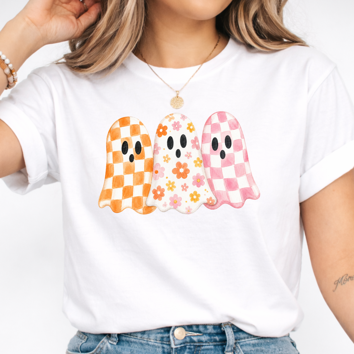 Woman wearing a white Halloween graphic tee with three orange, floral, and pink patterned ghosts.