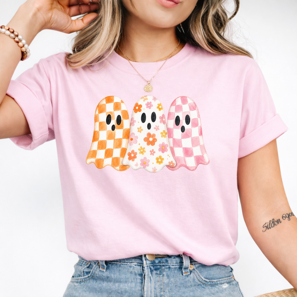 Woman wearing a light pink Halloween graphic tee with three orange, floral, and pink patterned ghosts.