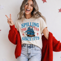 Woman wearing a t-shirt with a ship graphic and text, standing against a white background.