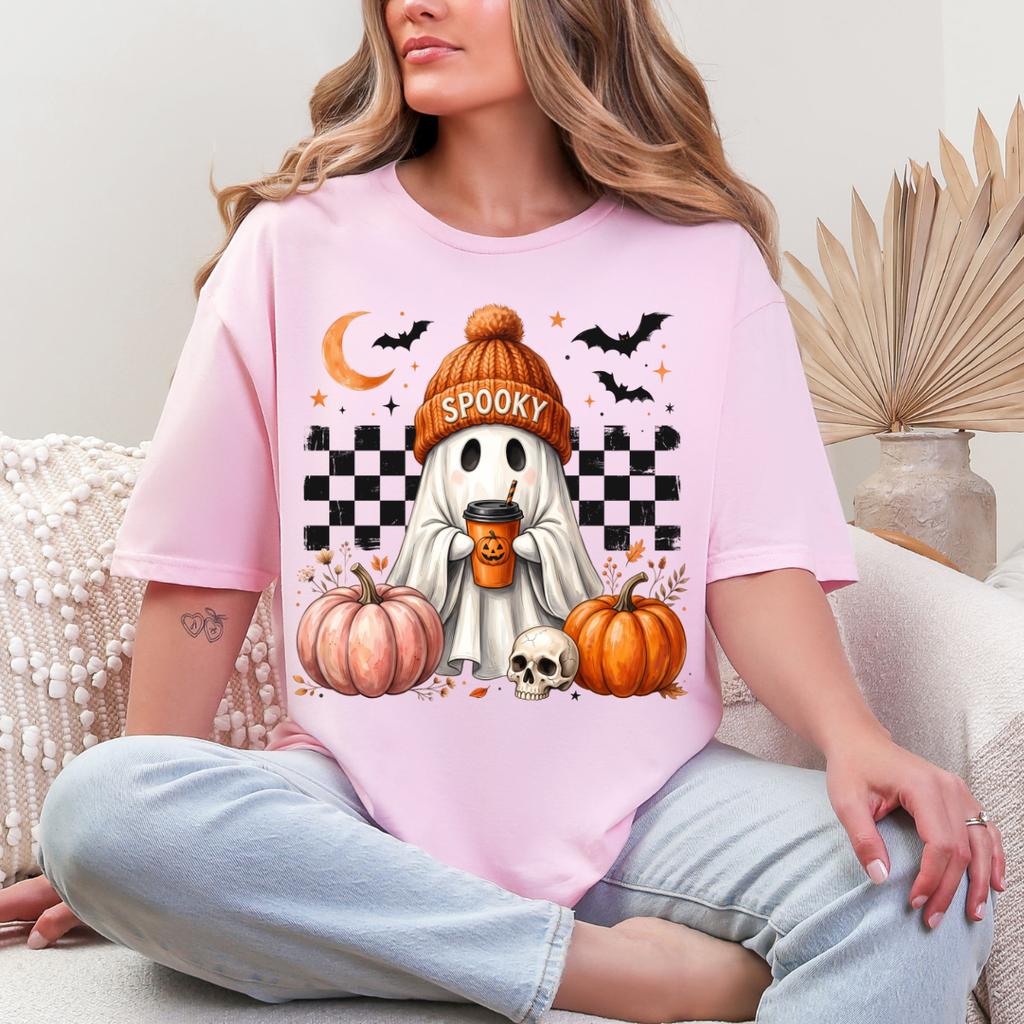 Woman wearing a light pink spooky ghost pumpkin coffee graphic tee with pumpkins, bats, and a ghost