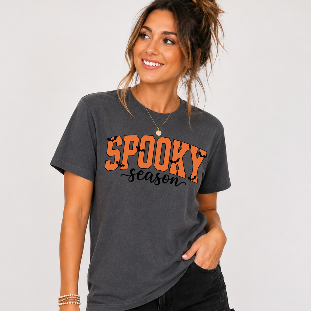 Woman wearing a charcoal Spooky Season Halloween graphic tee with orange lettering and black bats.