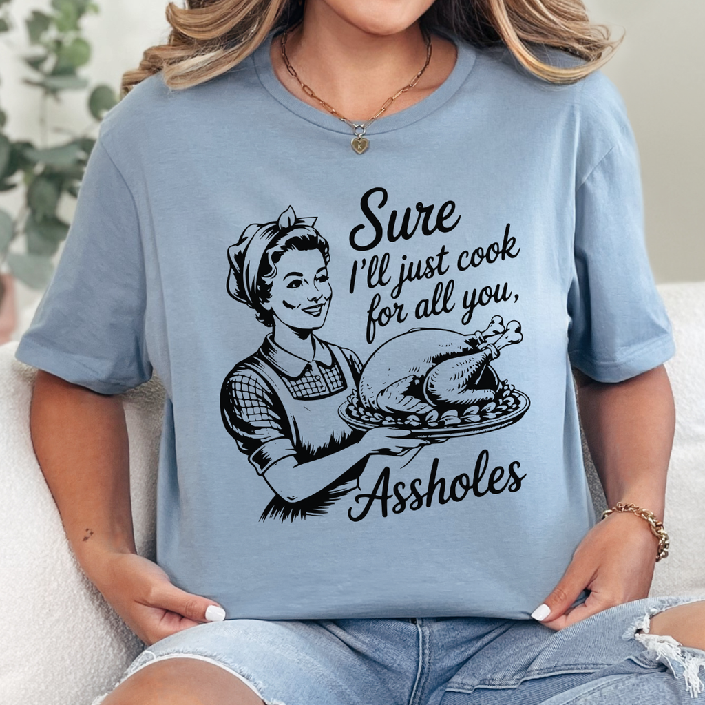 Woman wearing a stone blue funny Thanksgiving graphic tee with a retro hostess holding a roasted turkey