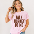 Woman wearing a white Talk Turkey to Me Thanksgiving graphic tee with distressed brown lettering