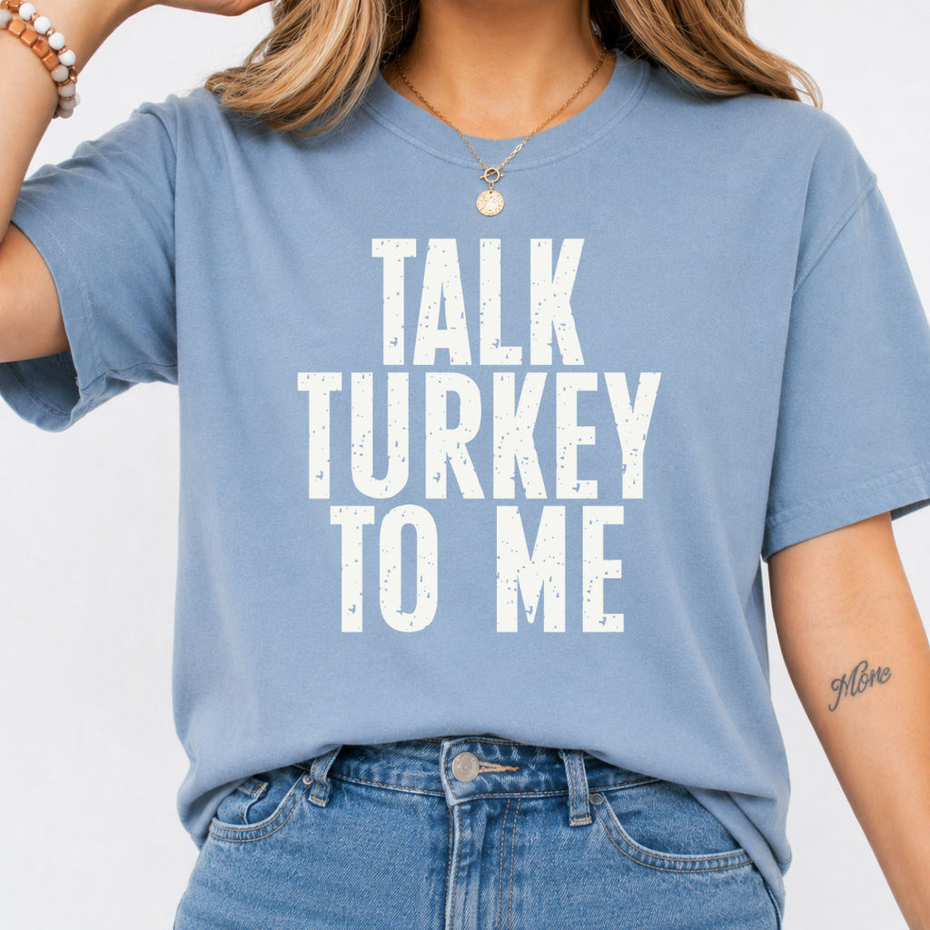 Woman wearing a stone blue Talk Turkey to Me Thanksgiving graphic tee with distressed brown lettering