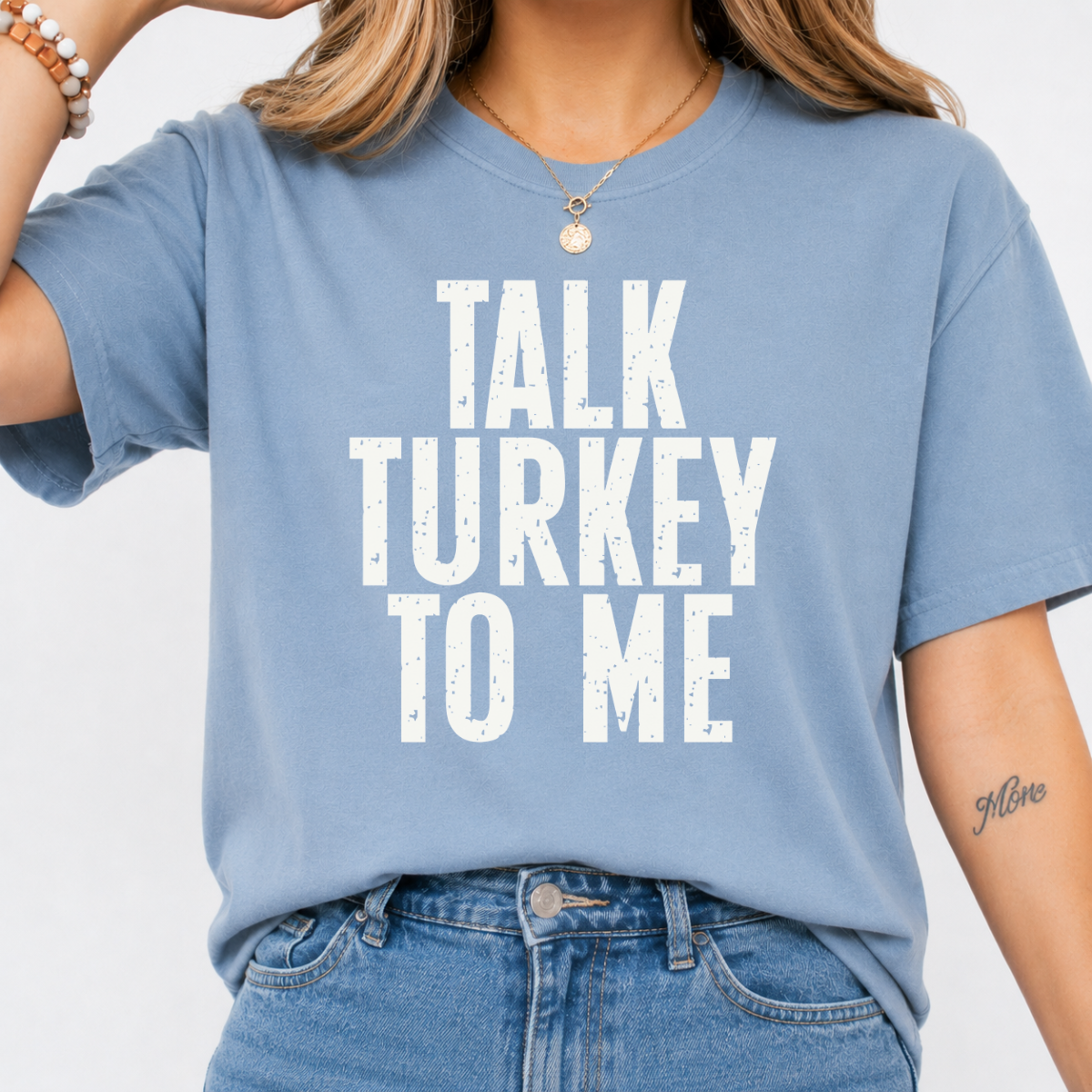 Woman wearing a stone blue Talk Turkey to Me Thanksgiving graphic tee with distressed brown lettering