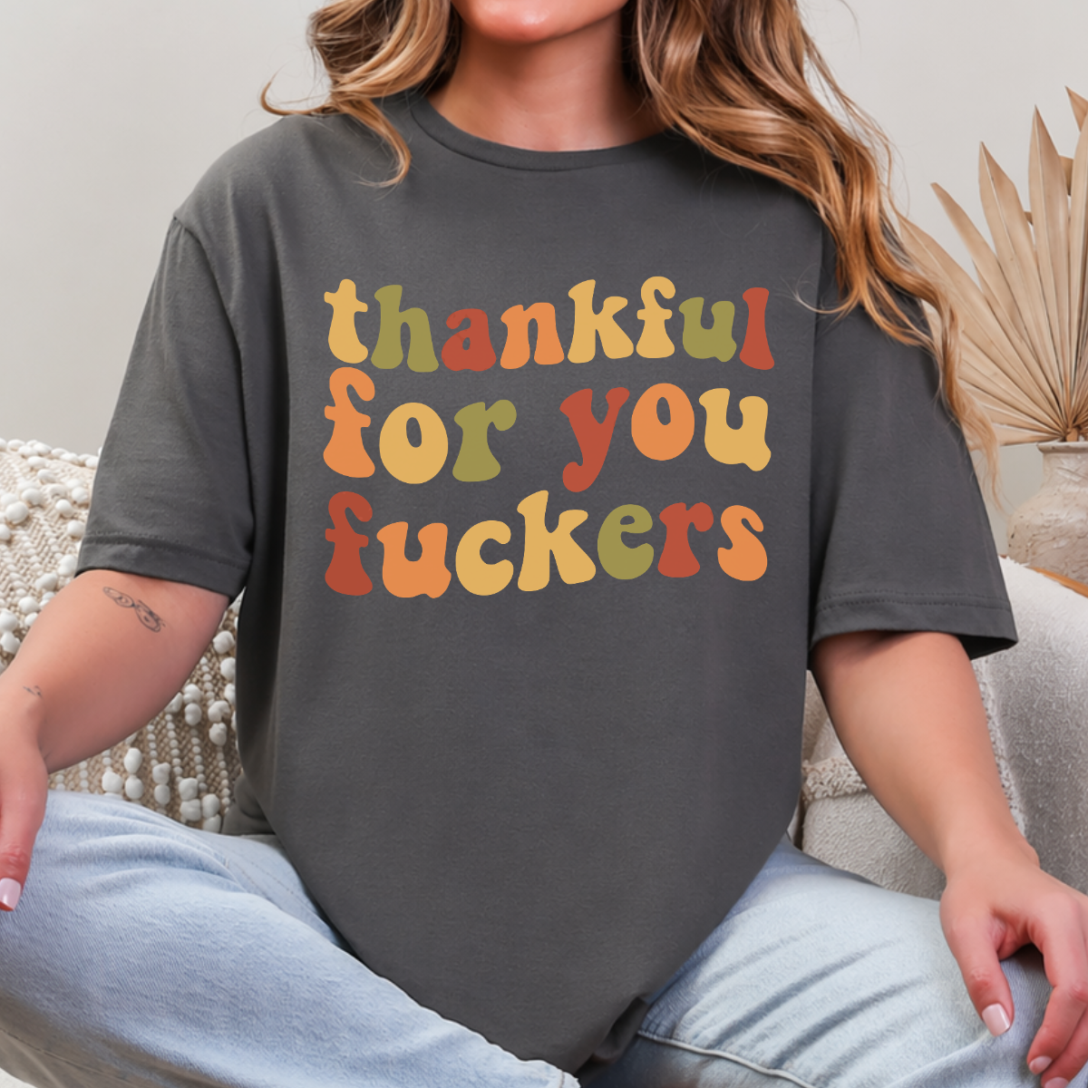 Woman wearing a charcoal Thankful for You Fuckers Thanksgiving graphic tee with colorful retro lettering.