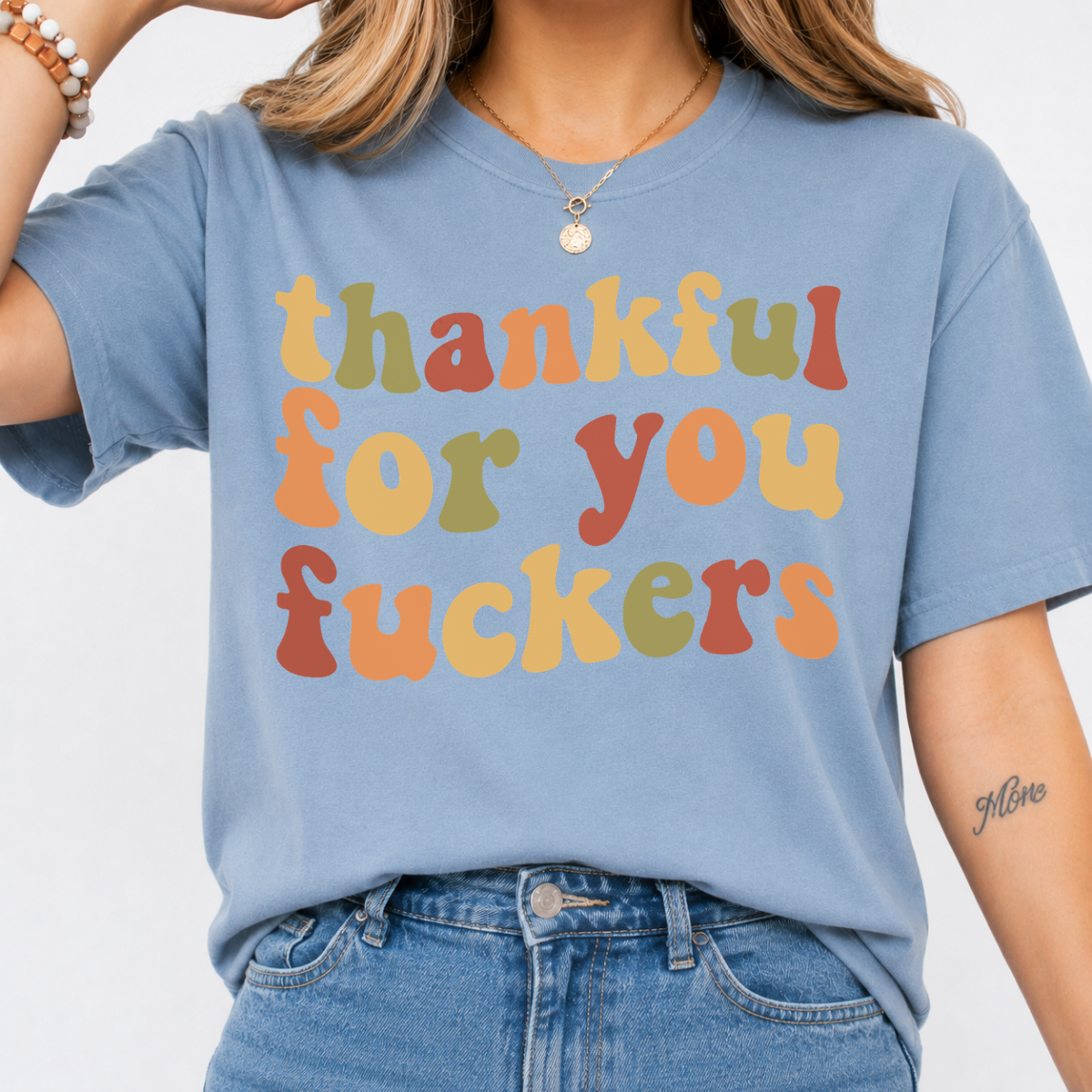 Woman wearing a stone blue Thankful for You Fuckers Thanksgiving graphic tee with colorful retro lettering.