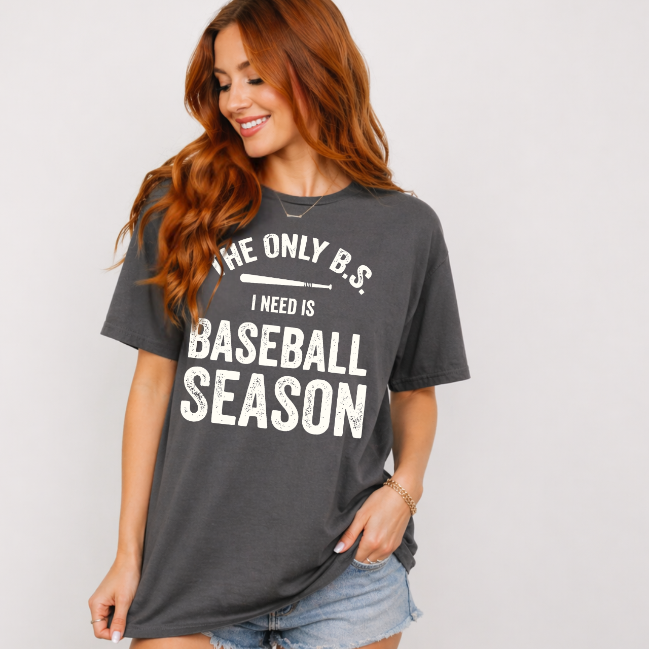 Woman wearing a gray t-shirt with a humorous baseball season quote that says "The Only B.S. I need is Baseball Season".