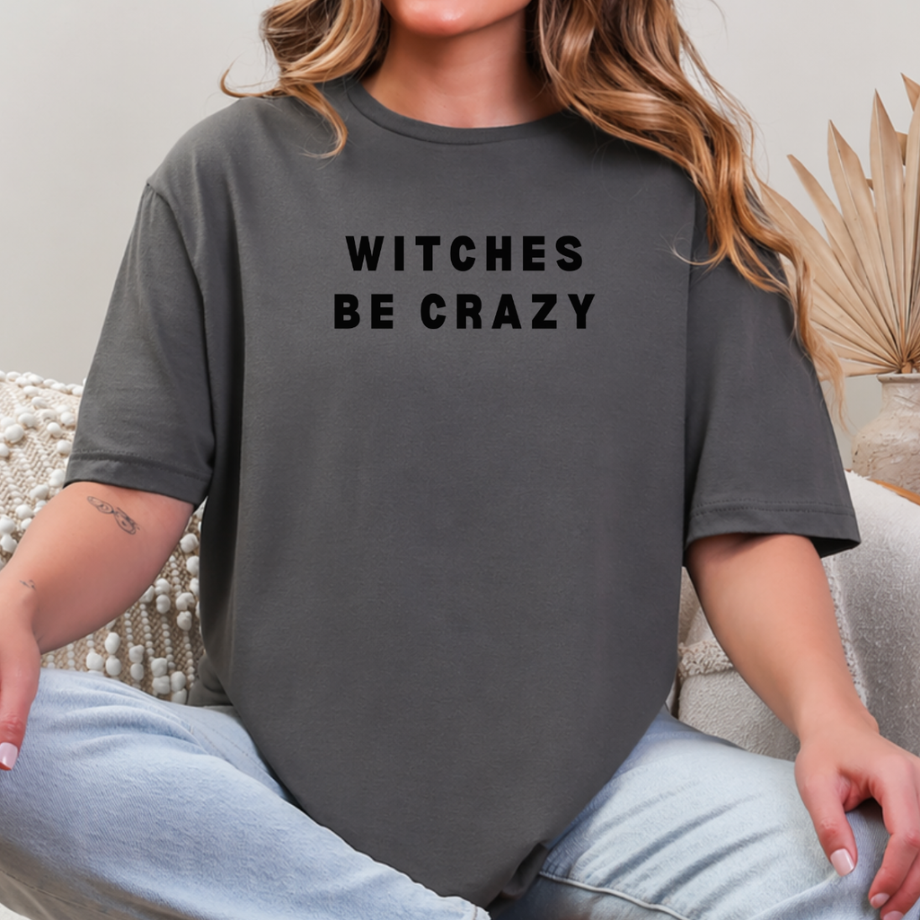 Woman wearing a charcoal Witches Be Crazy Halloween graphic tee with black lettering.