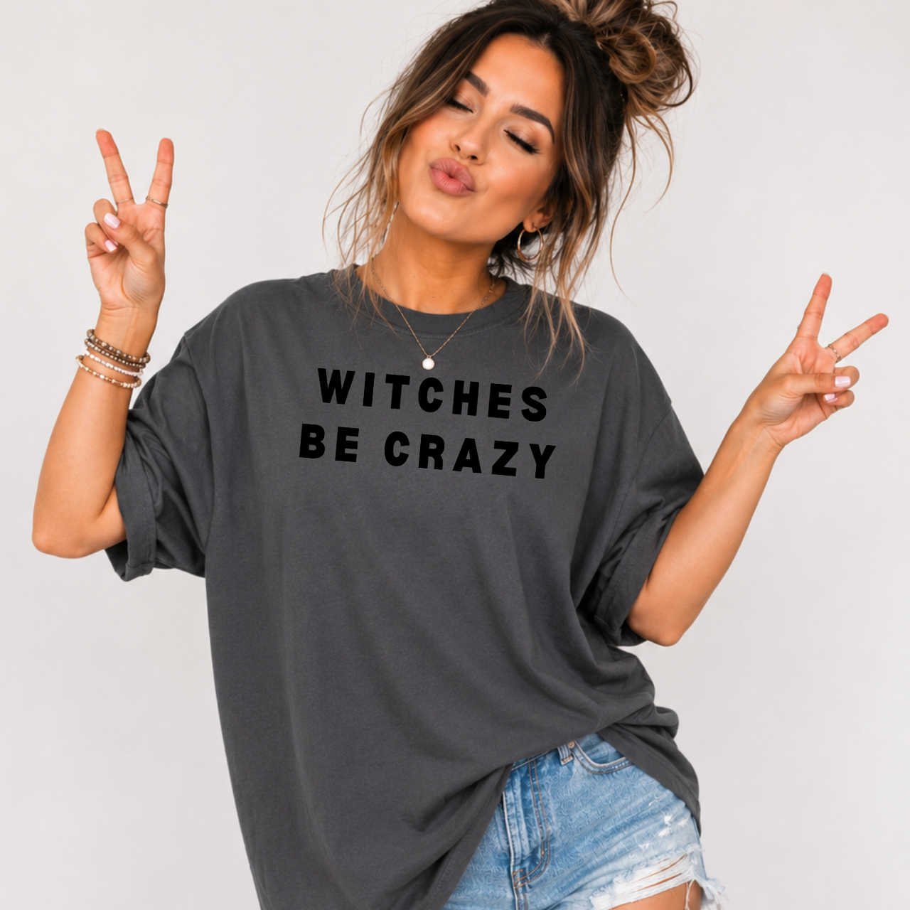 Woman wearing a charcoal Witches Be Crazy Halloween graphic tee with black lettering.