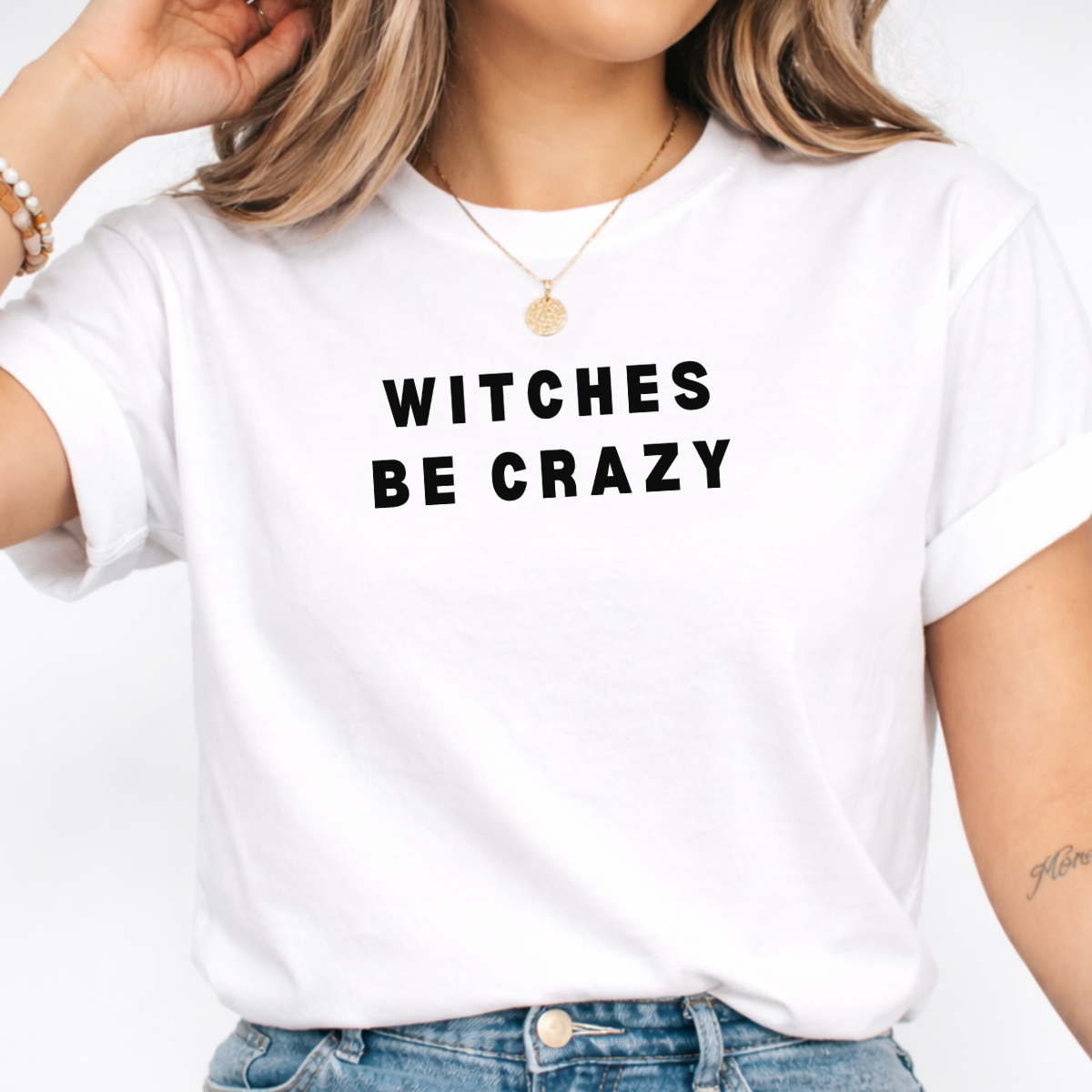Woman wearing a white Witches Be Crazy Halloween graphic tee with black lettering.